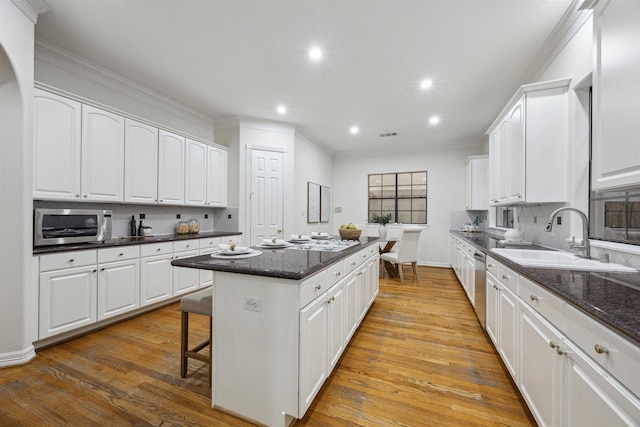 kitchen with white cabinets, a kitchen island, sink, and tasteful backsplash