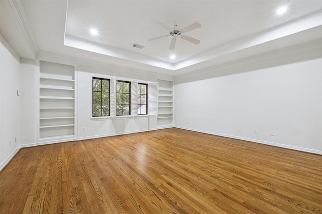 unfurnished room with hardwood / wood-style floors, a tray ceiling, and ceiling fan