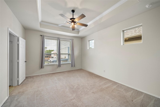 unfurnished bedroom with a tray ceiling, ceiling fan, light colored carpet, and ornamental molding