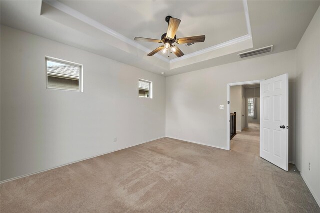 carpeted empty room featuring ceiling fan, ornamental molding, and a tray ceiling