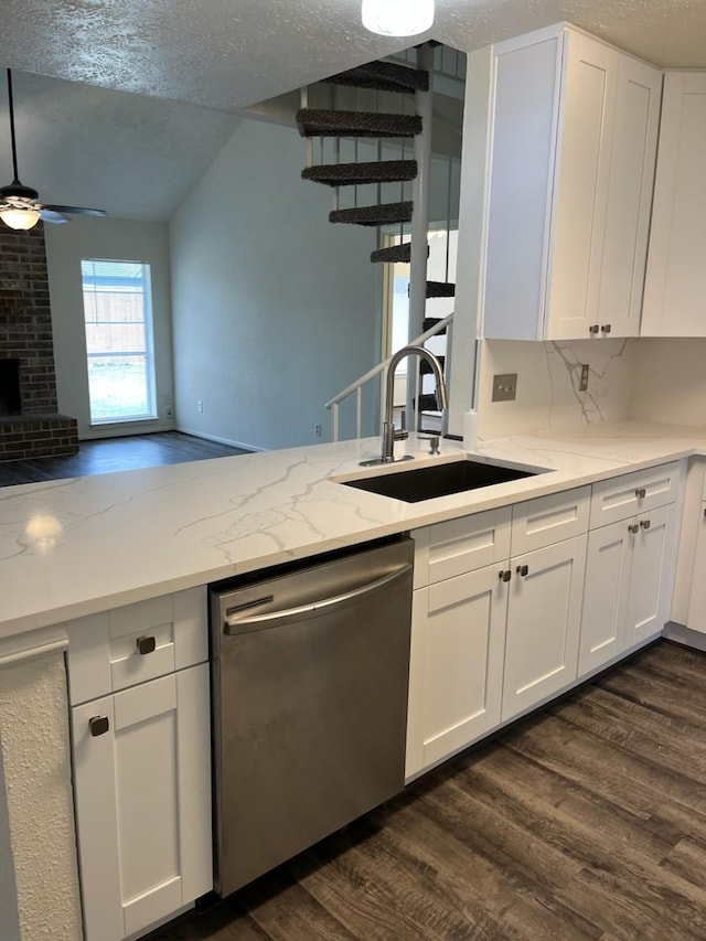 kitchen with sink, dark wood-type flooring, a brick fireplace, stainless steel dishwasher, and white cabinets