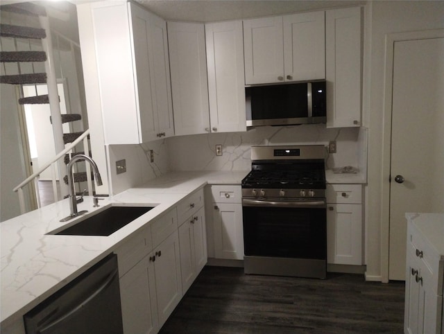 kitchen featuring white cabinetry, sink, light stone counters, and appliances with stainless steel finishes