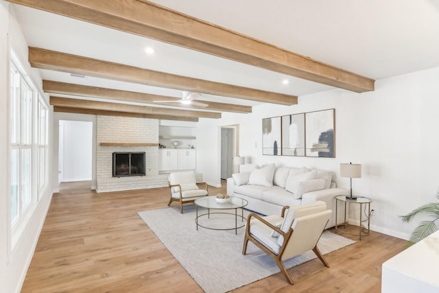 living room featuring a fireplace, beam ceiling, and light wood-type flooring