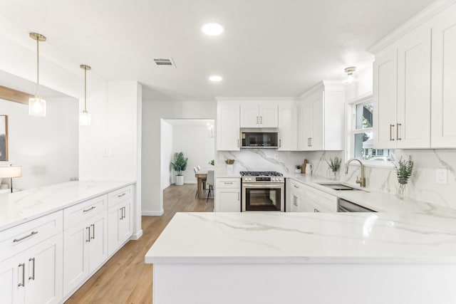 kitchen with pendant lighting, sink, white cabinetry, and stainless steel appliances