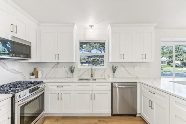 kitchen with white cabinets, appliances with stainless steel finishes, backsplash, and sink