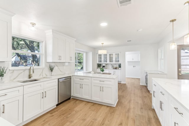 kitchen featuring white cabinetry, dishwasher, sink, hanging light fixtures, and decorative backsplash