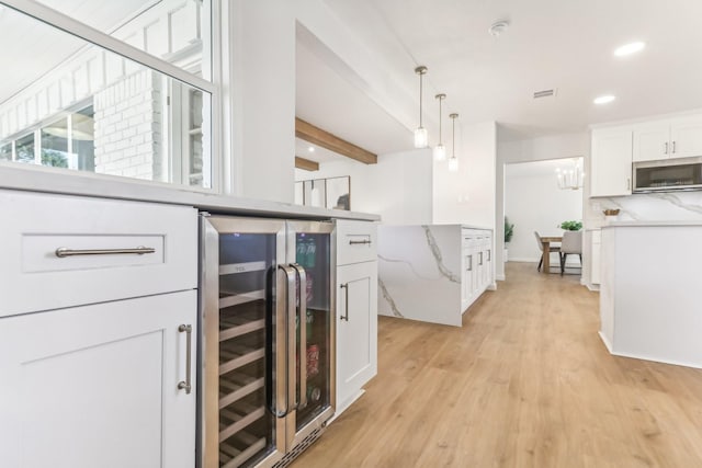 kitchen featuring white cabinets, hanging light fixtures, wine cooler, light hardwood / wood-style floors, and beam ceiling