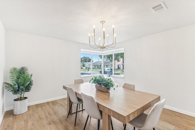 dining space featuring light hardwood / wood-style floors and an inviting chandelier