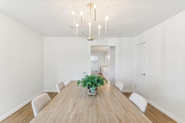 dining area featuring light wood-type flooring and an inviting chandelier