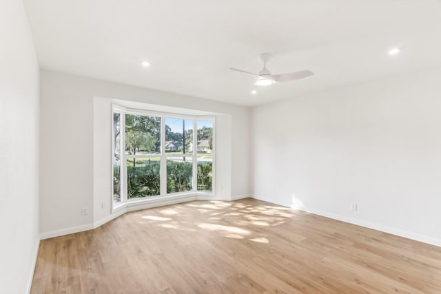 empty room with ceiling fan and light hardwood / wood-style flooring