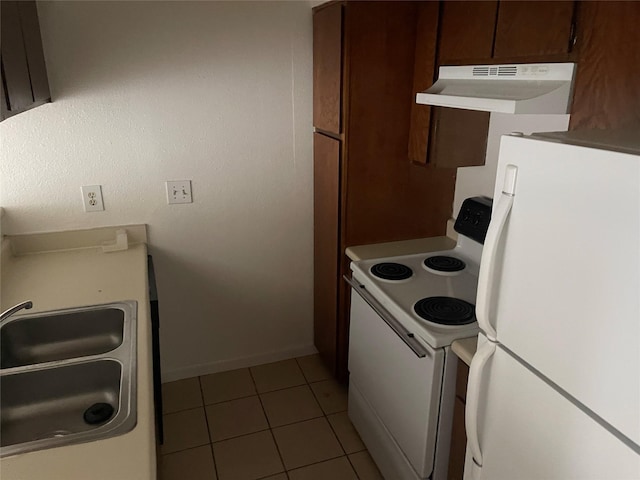 kitchen featuring dark brown cabinetry, white appliances, sink, and light tile patterned floors