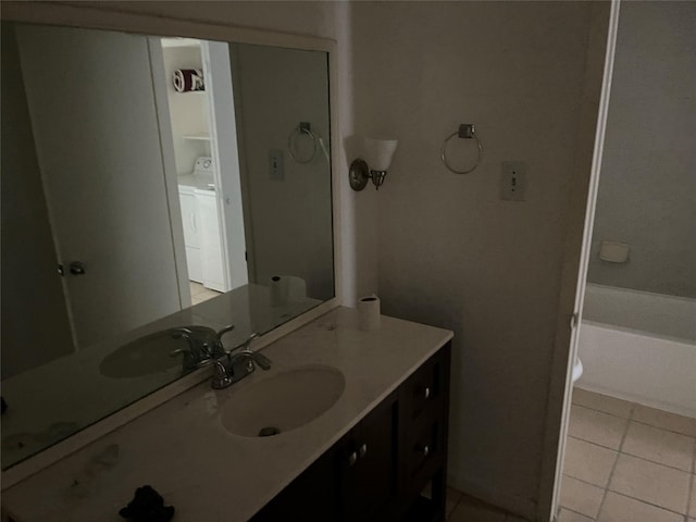 bathroom with tile patterned flooring, vanity, and washer / dryer