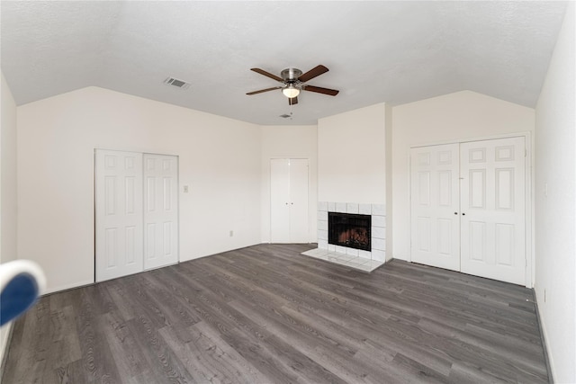 unfurnished living room with a tile fireplace, ceiling fan, dark wood-type flooring, and vaulted ceiling