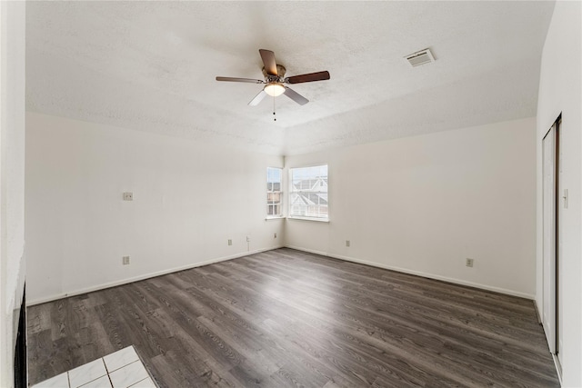 empty room featuring ceiling fan, dark hardwood / wood-style floors, and a textured ceiling