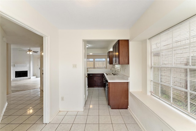 kitchen with a fireplace, ceiling fan, sink, and light tile patterned flooring