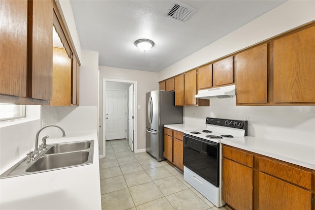 kitchen featuring white electric stove, visible vents, freestanding refrigerator, under cabinet range hood, and a sink