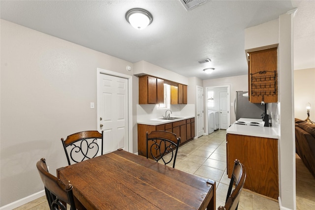 dining room with sink, light tile patterned flooring, a textured ceiling, and independent washer and dryer