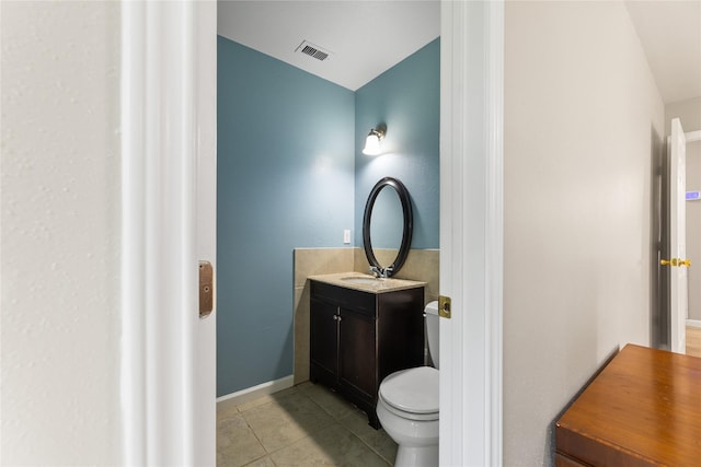 half bath featuring tile patterned flooring, toilet, visible vents, vanity, and baseboards