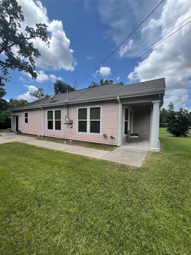 rear view of house featuring a yard and a patio