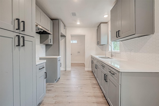 kitchen featuring gray cabinets, light wood-type flooring, and sink