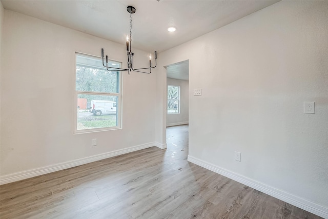 unfurnished dining area with hardwood / wood-style floors and an inviting chandelier