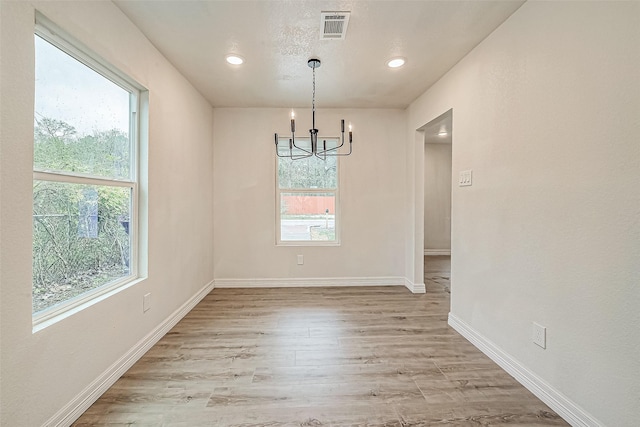 unfurnished dining area featuring light hardwood / wood-style floors and a notable chandelier