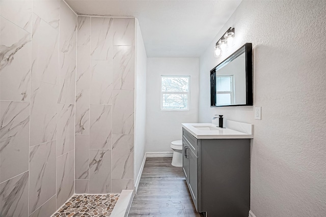 bathroom featuring tiled shower, wood-type flooring, vanity, and toilet