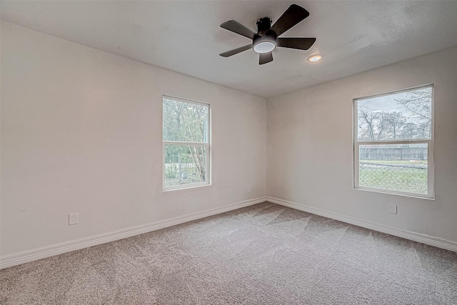 carpeted spare room featuring ceiling fan and a wealth of natural light