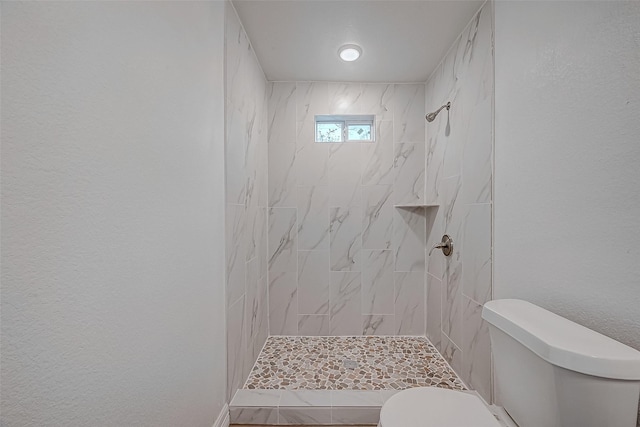 bathroom with tiled shower and toilet