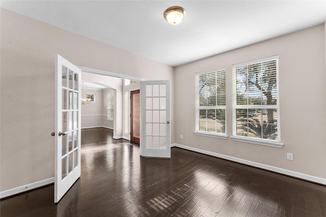 empty room with dark hardwood / wood-style floors and french doors