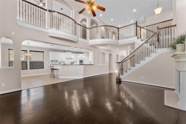 unfurnished living room featuring a high ceiling, wood-type flooring, and ceiling fan