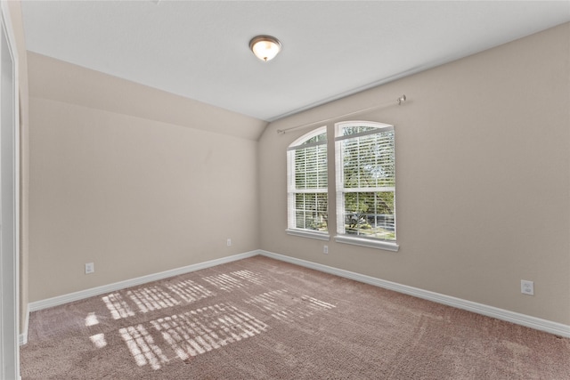 unfurnished room featuring lofted ceiling and carpet flooring