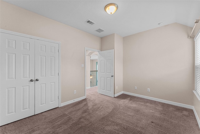 unfurnished bedroom with a closet, lofted ceiling, and carpet