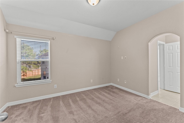 unfurnished room featuring vaulted ceiling and light carpet