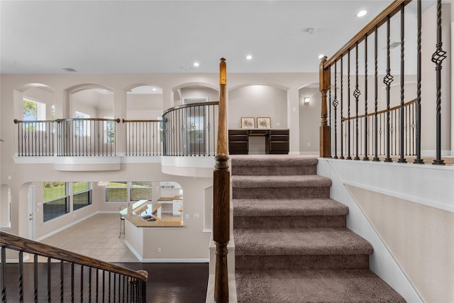 staircase with hardwood / wood-style flooring and a towering ceiling