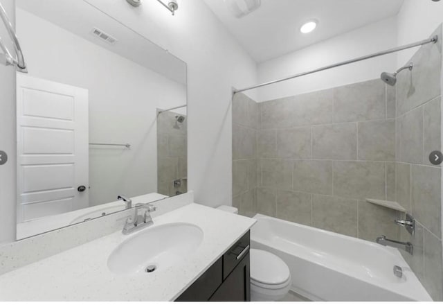 full bathroom featuring vanity, tiled shower / bath combo, and toilet