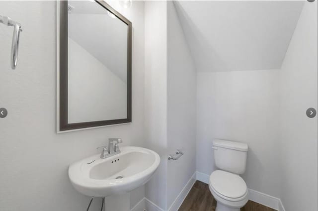 bathroom featuring hardwood / wood-style flooring, sink, lofted ceiling, and toilet