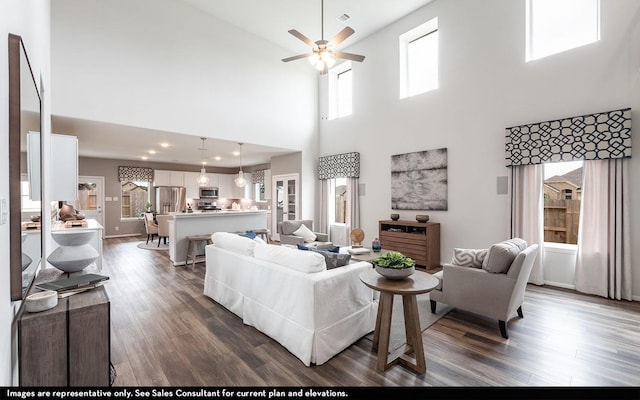 living room featuring ceiling fan, dark hardwood / wood-style floors, and a high ceiling