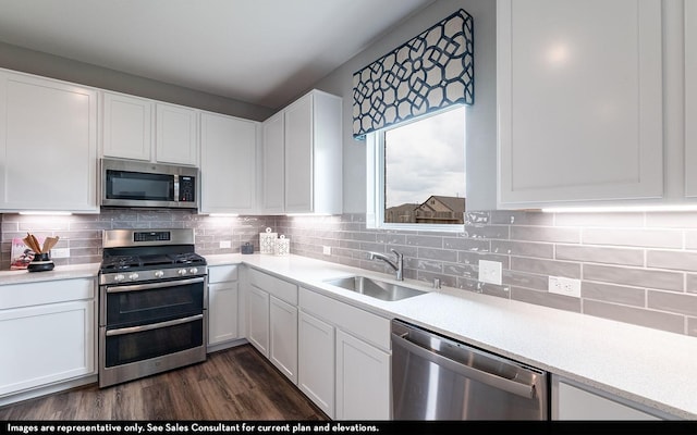 kitchen with sink, dark hardwood / wood-style floors, decorative backsplash, white cabinetry, and stainless steel appliances