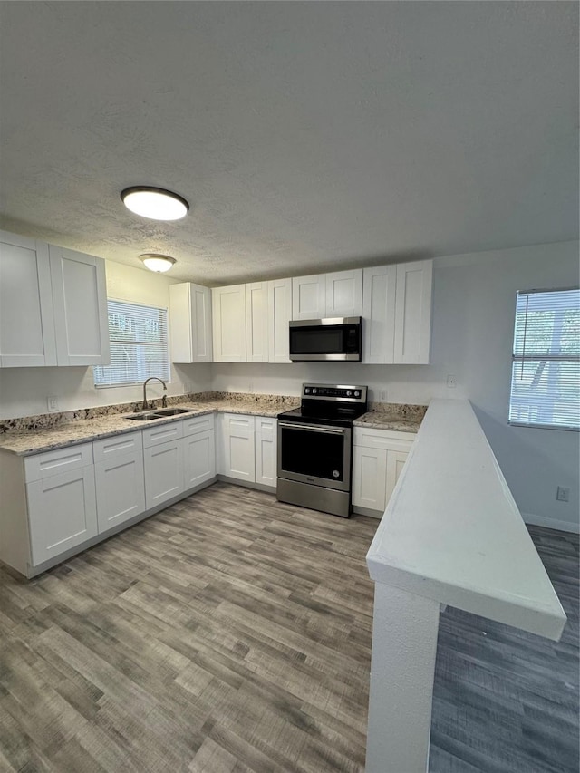 kitchen featuring a healthy amount of sunlight, sink, white cabinets, and stainless steel appliances