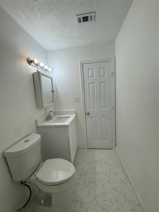 bathroom featuring vanity, a textured ceiling, and toilet