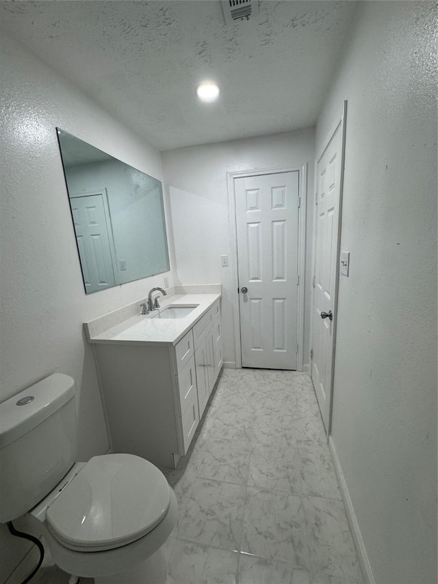 bathroom featuring a textured ceiling, vanity, and toilet