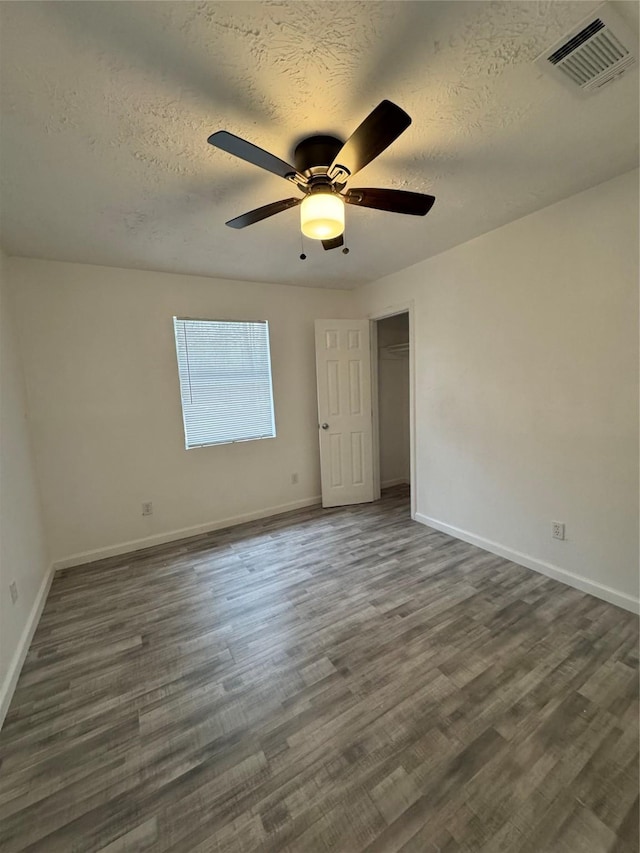 empty room featuring a textured ceiling, dark hardwood / wood-style flooring, and ceiling fan