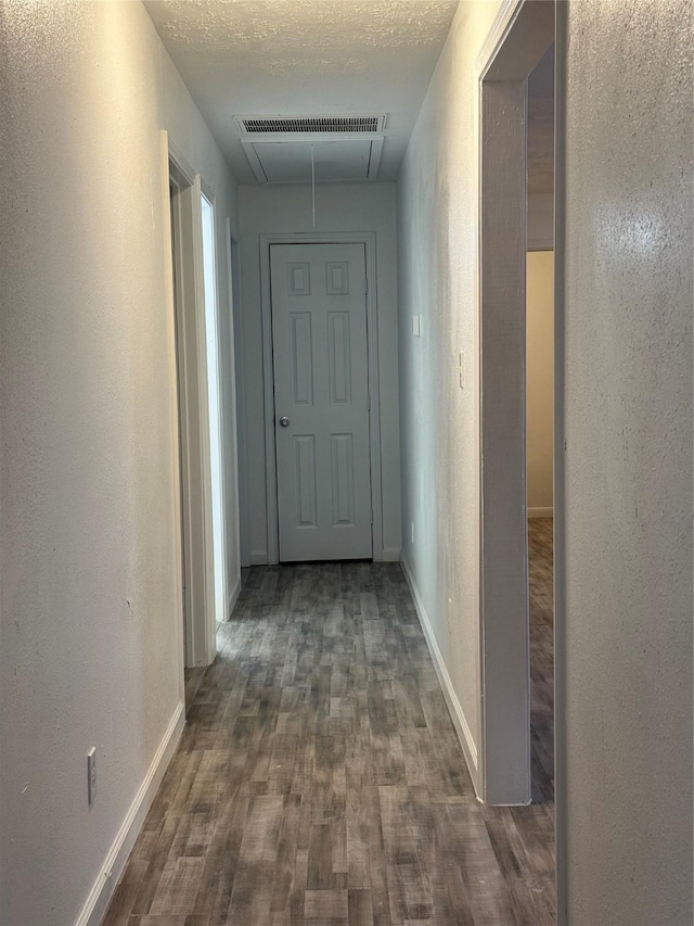 hall featuring a textured ceiling and dark hardwood / wood-style floors