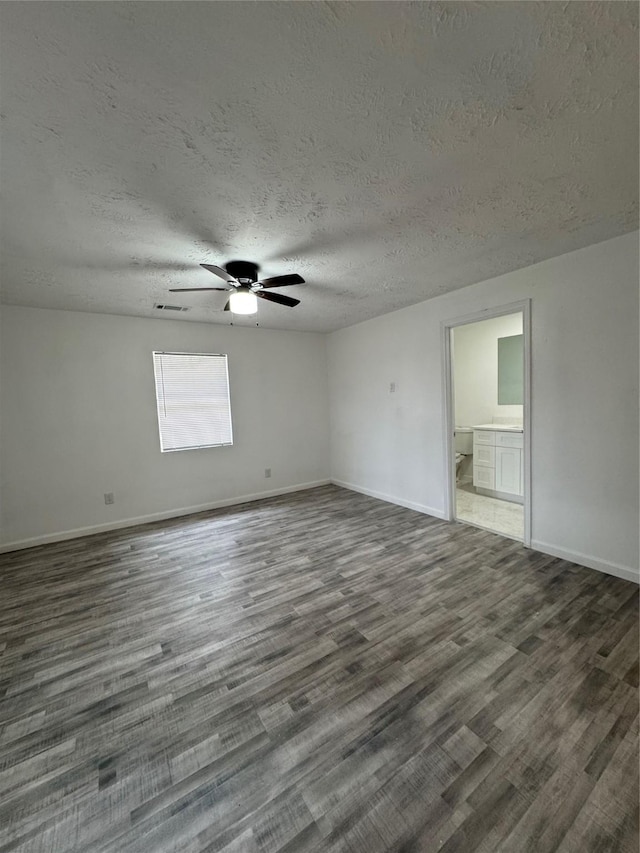 spare room featuring a textured ceiling and dark hardwood / wood-style floors