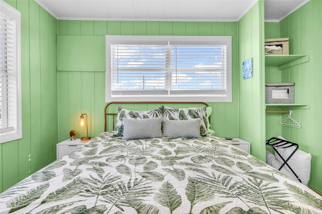 bedroom with multiple windows, wood walls, and ornamental molding