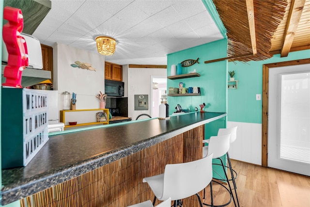 kitchen with beamed ceiling, light hardwood / wood-style flooring, and wooden walls