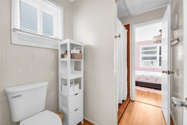 bathroom with toilet, wood-type flooring, and crown molding