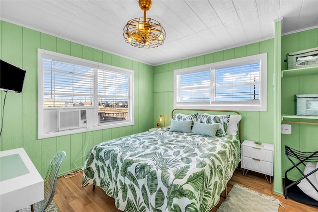 bedroom with hardwood / wood-style floors, cooling unit, and wood walls