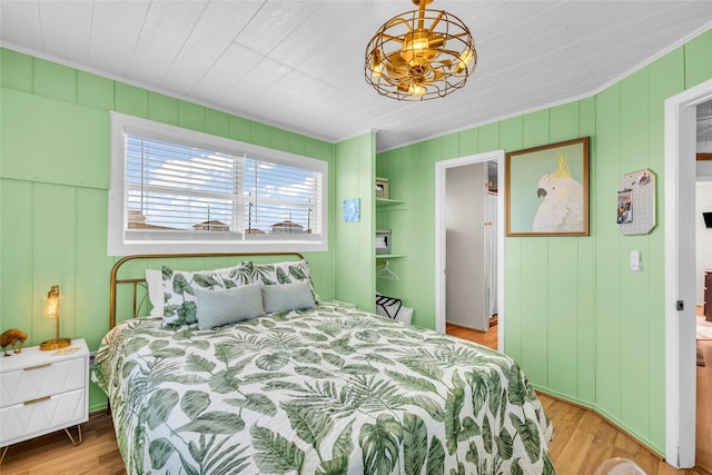 bedroom with light wood-type flooring and wood walls